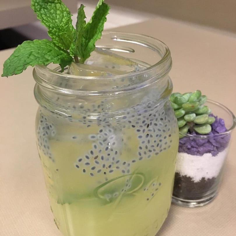 A Thai basil seed drink with mint garnish in a mason jar next to a small succulent.